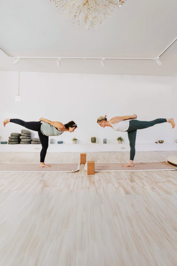 Zwei Frauen die die Waagen-Asana ausüben