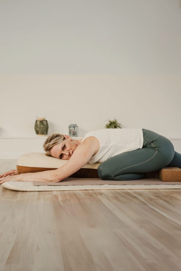 Eine Frau in Schwanen-Asana gestützt auf ein Bolster