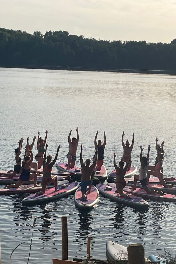 SUP Yoga Kurs auf dem Wasser alle sind im tiefen Ausfallschritt